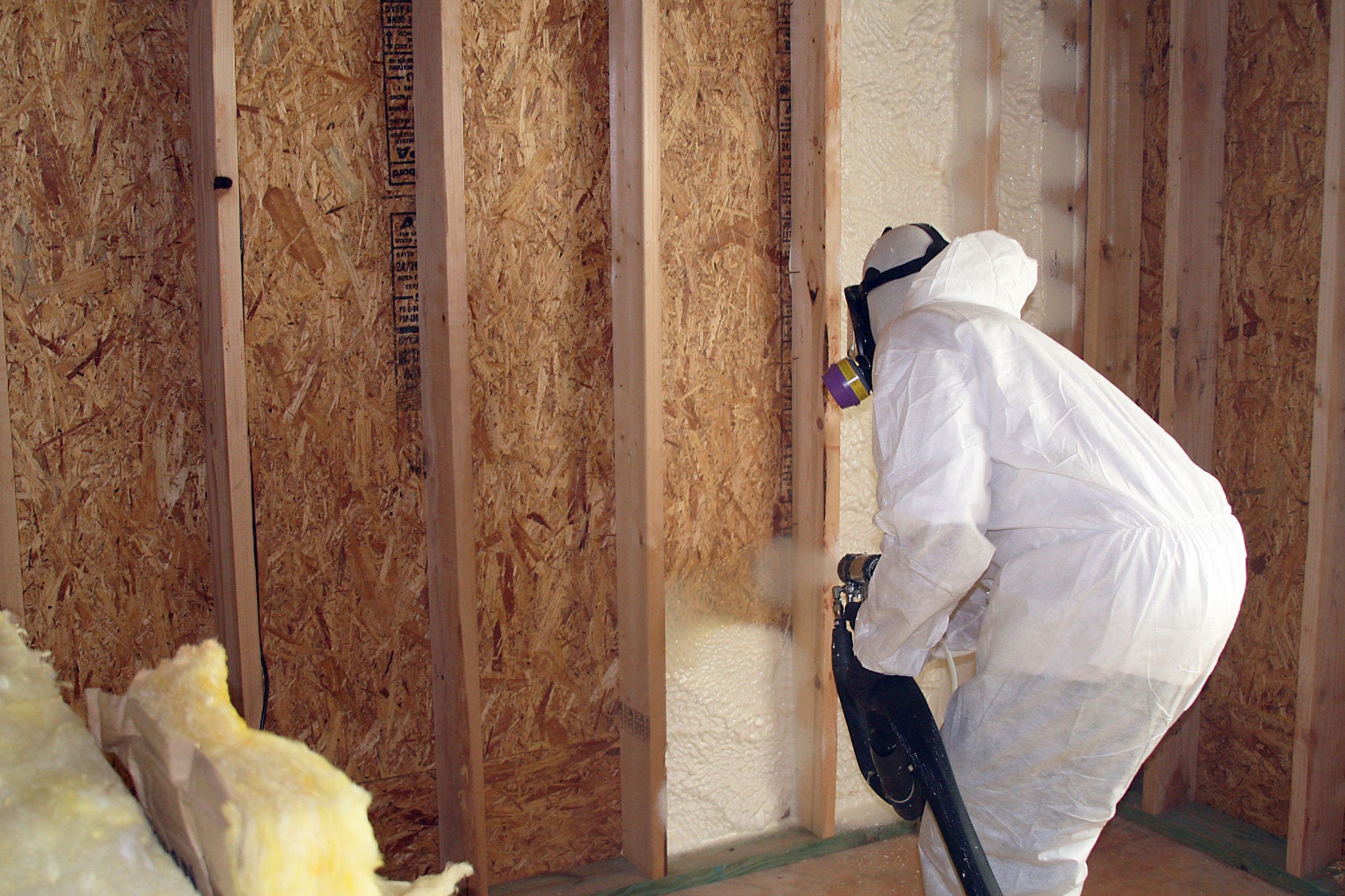 Man applying spray foam insulation with blower