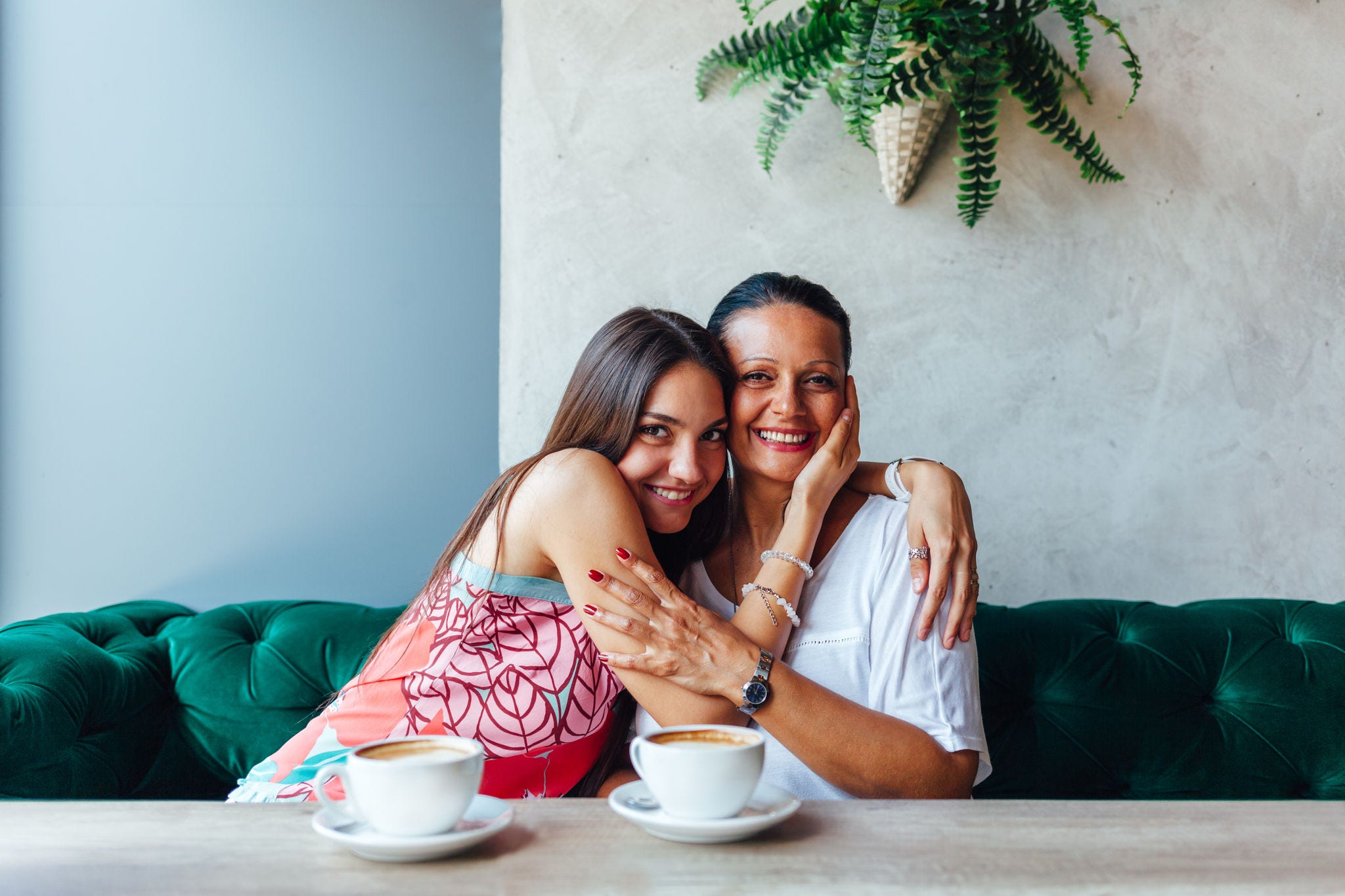 Mother and daughter embracing. Aged woman and her adult daughter drinking coffee at cafe. Mothers day.