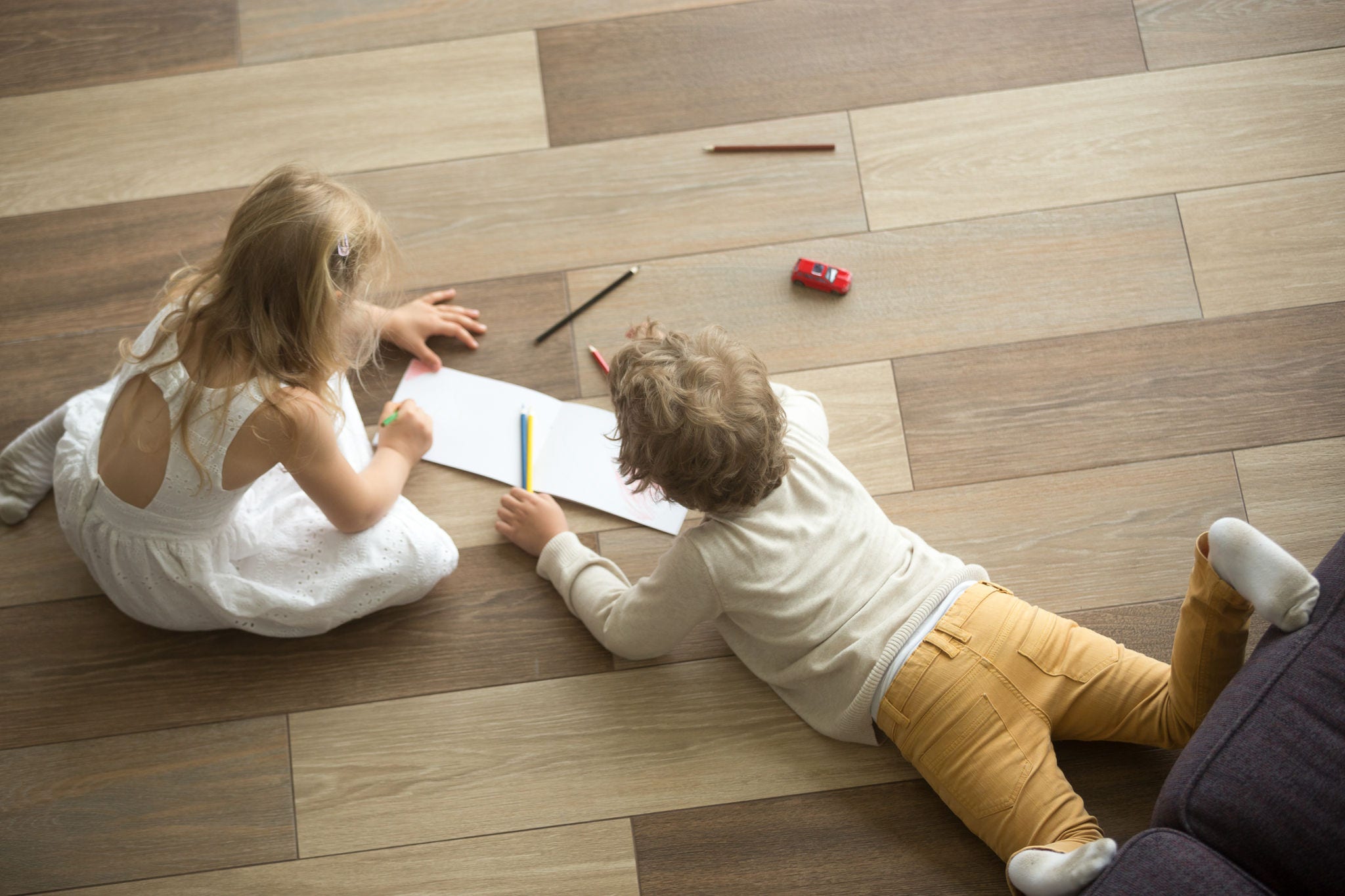 Kids playing drawing together on floor at home, top view 