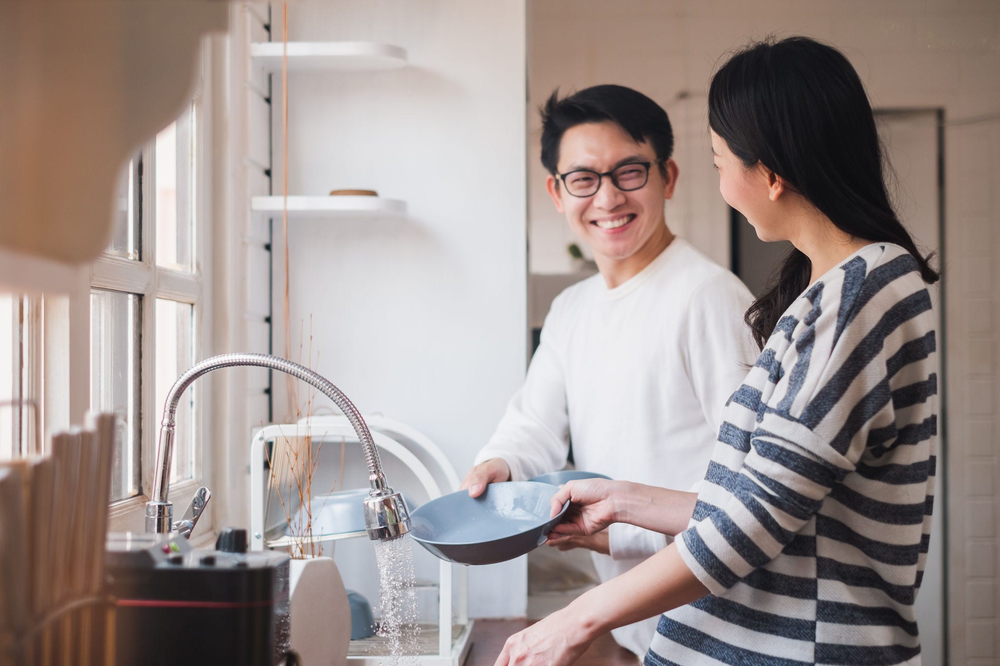 Asian couple washing dishes together at kitchen