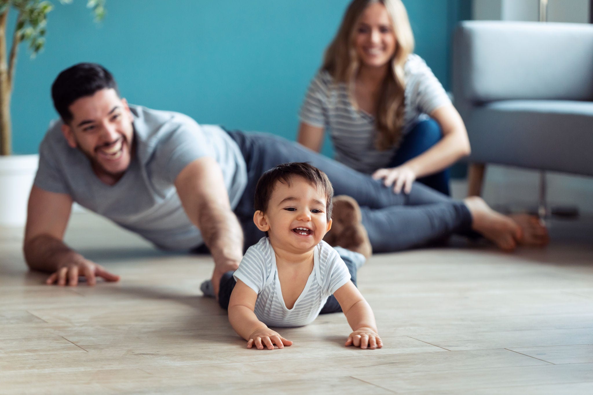 Pais brincando com o bebê sentados no chão em casa