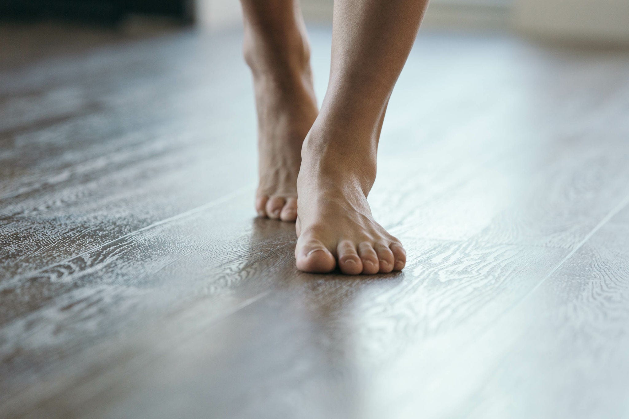 Person Walking on Wooden Floor Barefoot. Heated Flooring